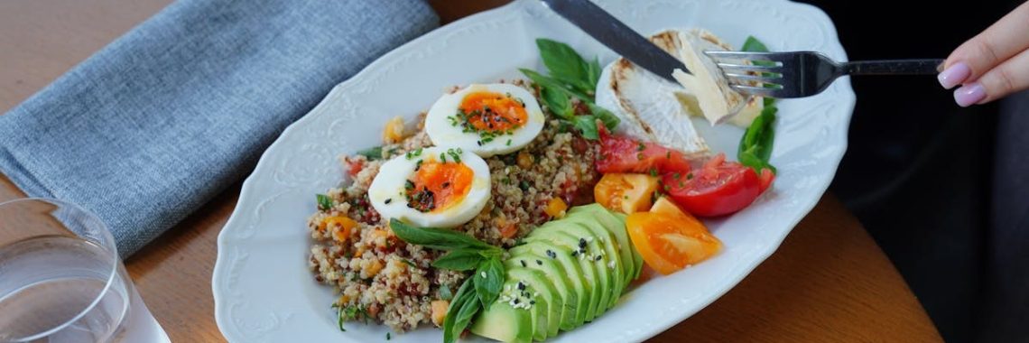 A delicious and healthy breakfast featuring avocado, eggs, and coffee served on a wooden table.